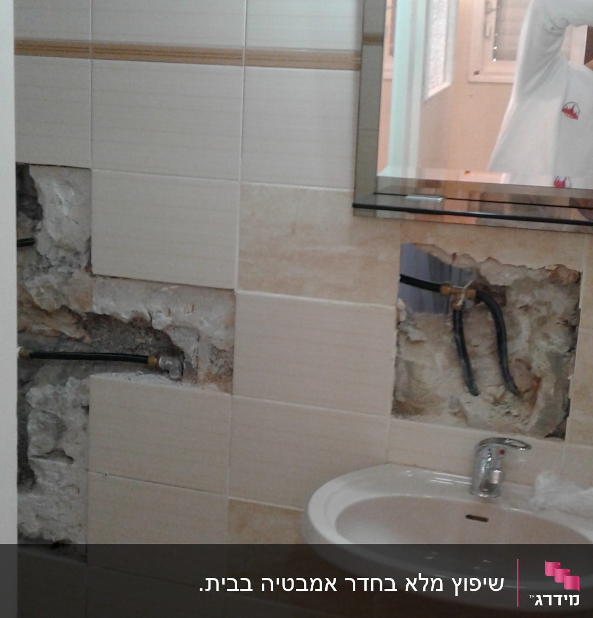 קיר אמבטיה עם אריחים שבורים וצנרת חשופה